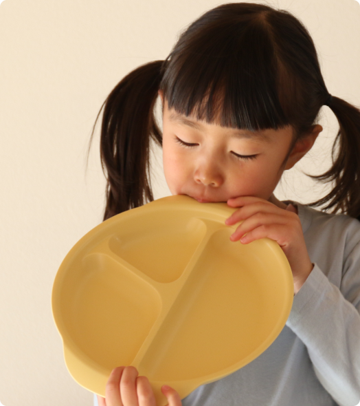 子供がランチ皿をかじっている